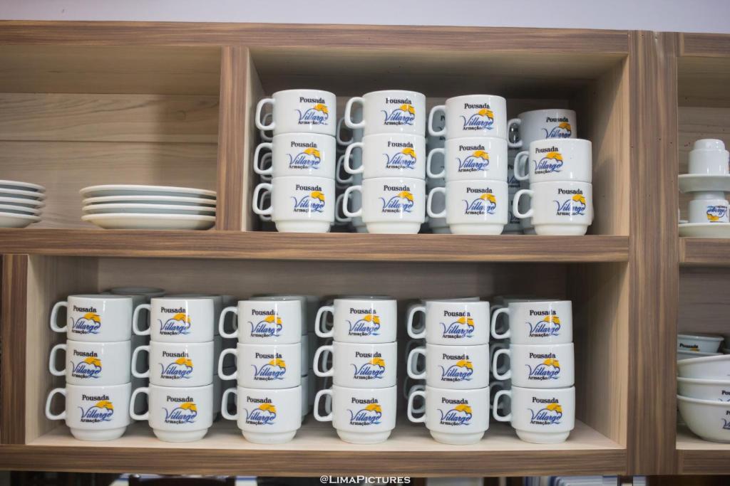 Canecas e louças da pousada organizadas na prateleira